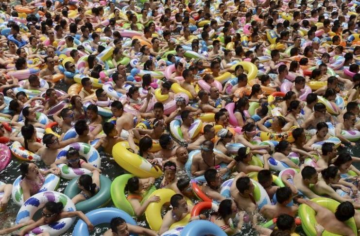 Visitors crowd an artificial wave swimming pool at a tourist resort to escape the summer heat in Daying county of Suining