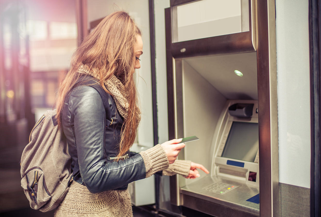 Young woman taking money from ATM