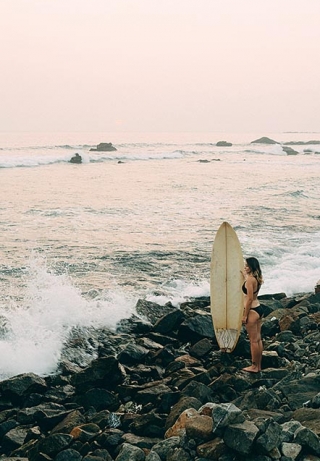 Woman on the beach with surfboard in Sri Lanka