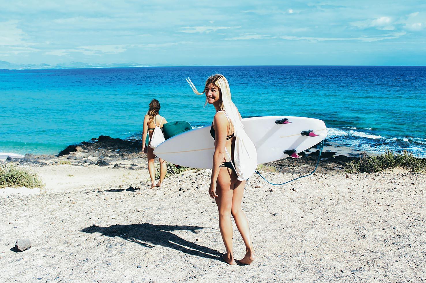 Surfer girls going to the sea